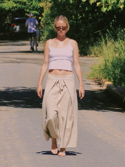 Woman walking outdoors wearing a light-colored top and organic cotton flowy pants.
